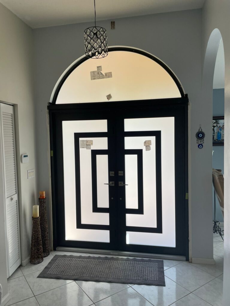 Black and white geometric entry door beneath an arched transom, seen from inside the hallway