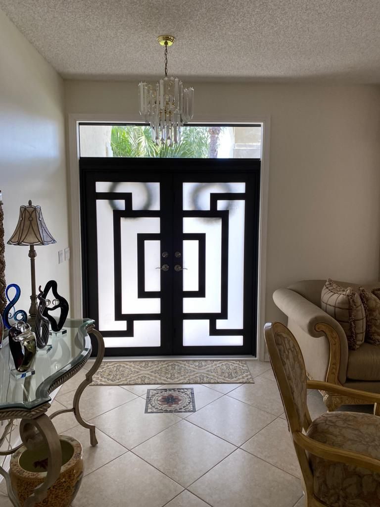 Black geometric double entry door with full-height sidelights, seen from the entrance hall looking out