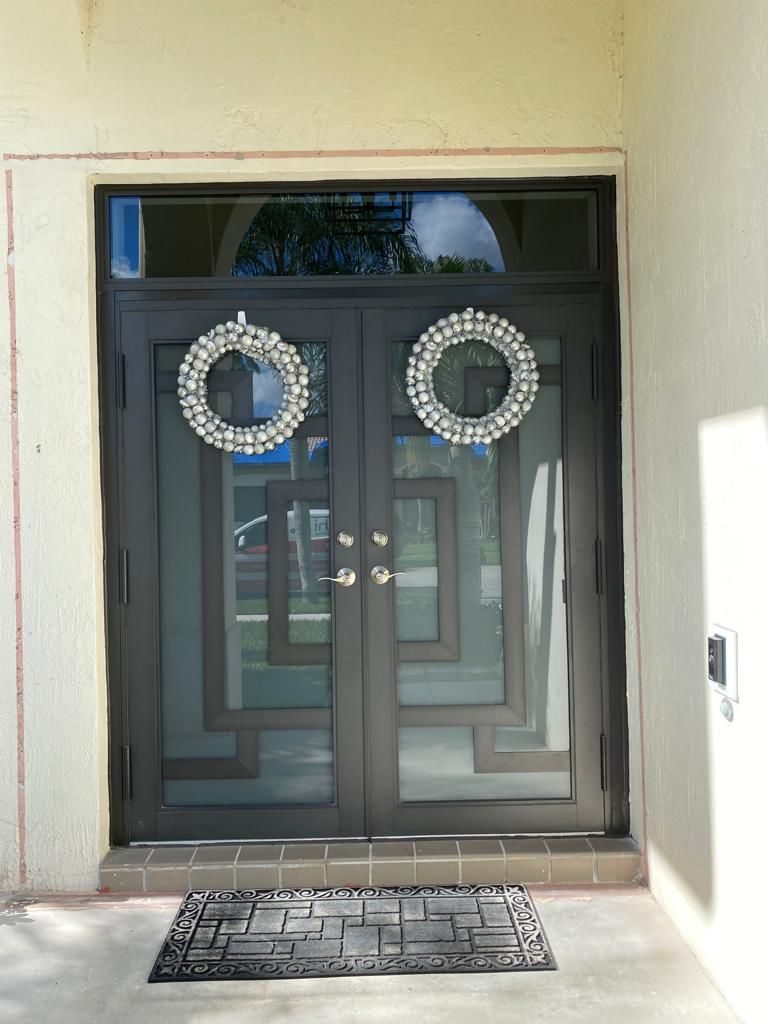 Dark double entry doors with glazed panels under an arched transom light, seen from outside