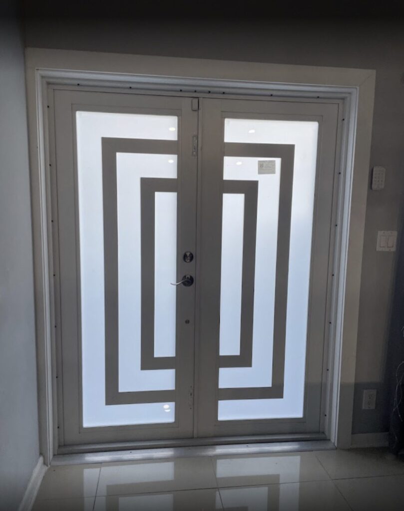 Geometric-pattern double entry door with matching sidelights viewed from inside a tiled entrance hall