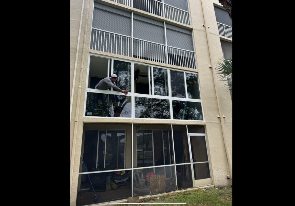 Glazed opening being installed in a building elevation, with the installer working from outside at the head of the frame