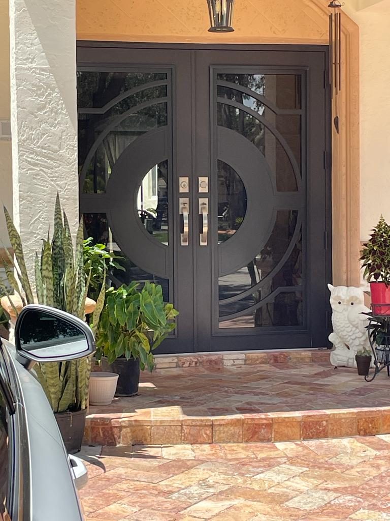 Timber-framed entry door with a circular glazed light, set behind a terracotta-paved porch
