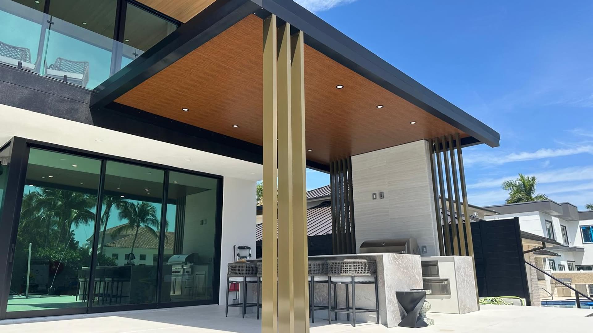 Covered outdoor structure part-built on open ground, showing the frame, the timber soffit lining and the ground still to be surfaced