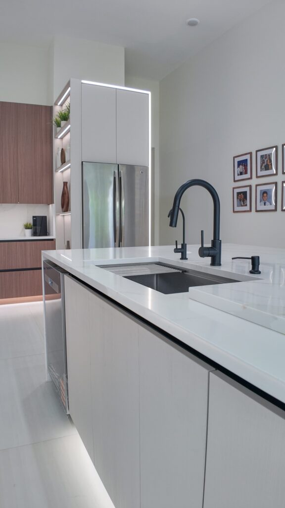 Undermount sink set into the stone island worktop with a matt black tap and integrated dishwasher alongside