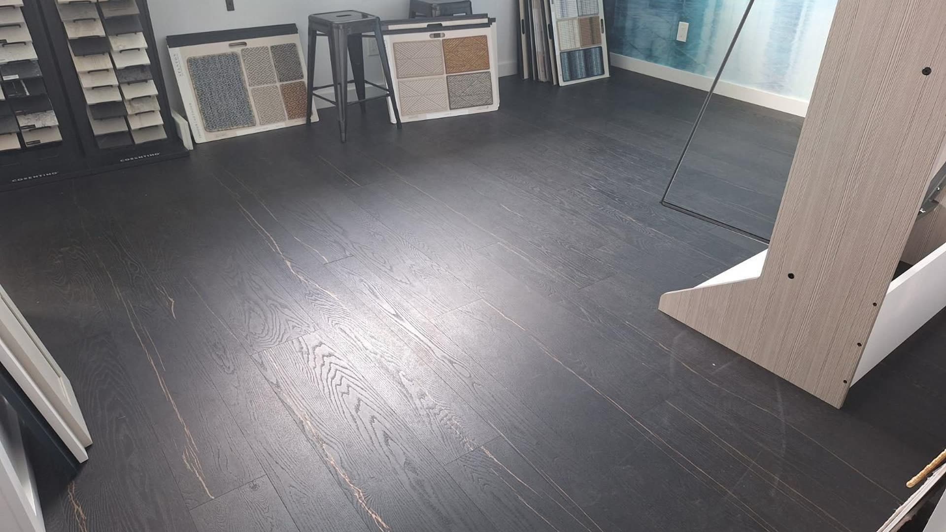 Flooring sample boards and display panels standing on a dark plank floor during material selection