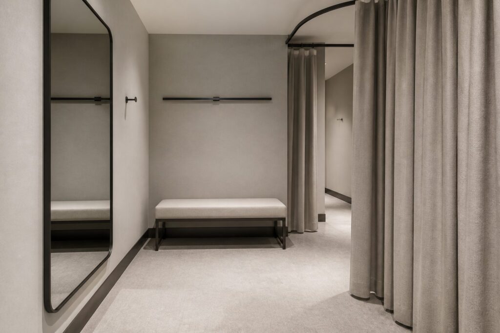 Illustration of a retail fitting room with a bench, mirror and clear floor space