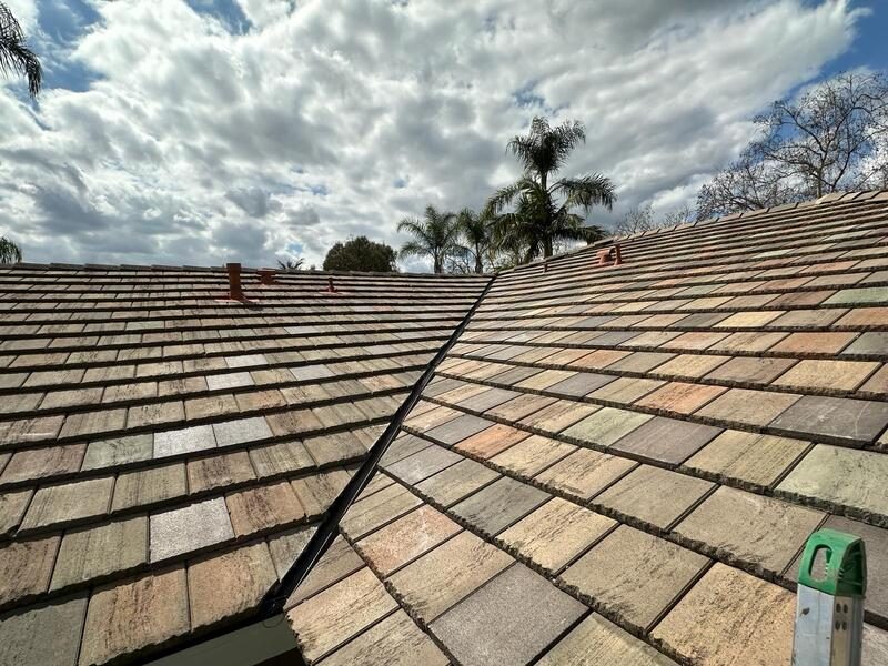 Low-profile flat tile roof running to a hip, showing the flatter alternative to a barrel or S-tile profile