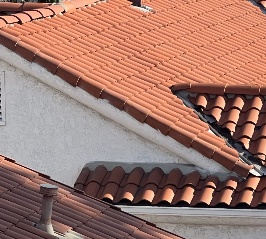 Close view of a barrel tile roof plane meeting a rendered wall, with the tile cut and closed against it
