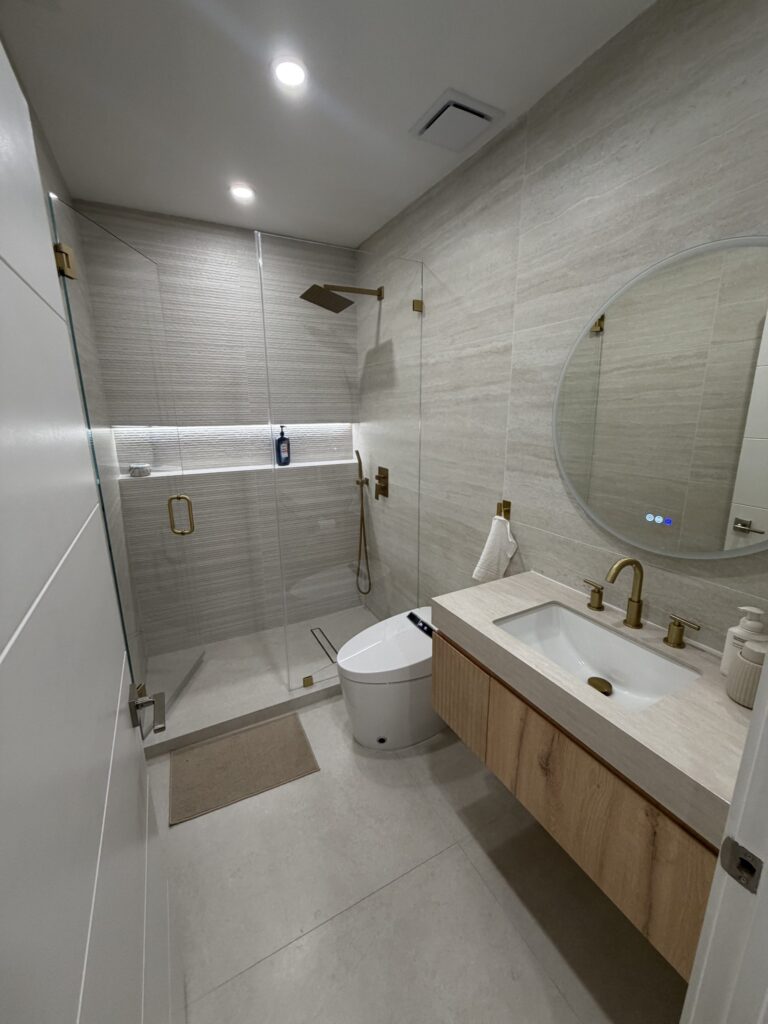 Finished bathroom seen from the doorway, with the walk-in shower, vanity and wall-hung toilet in one view