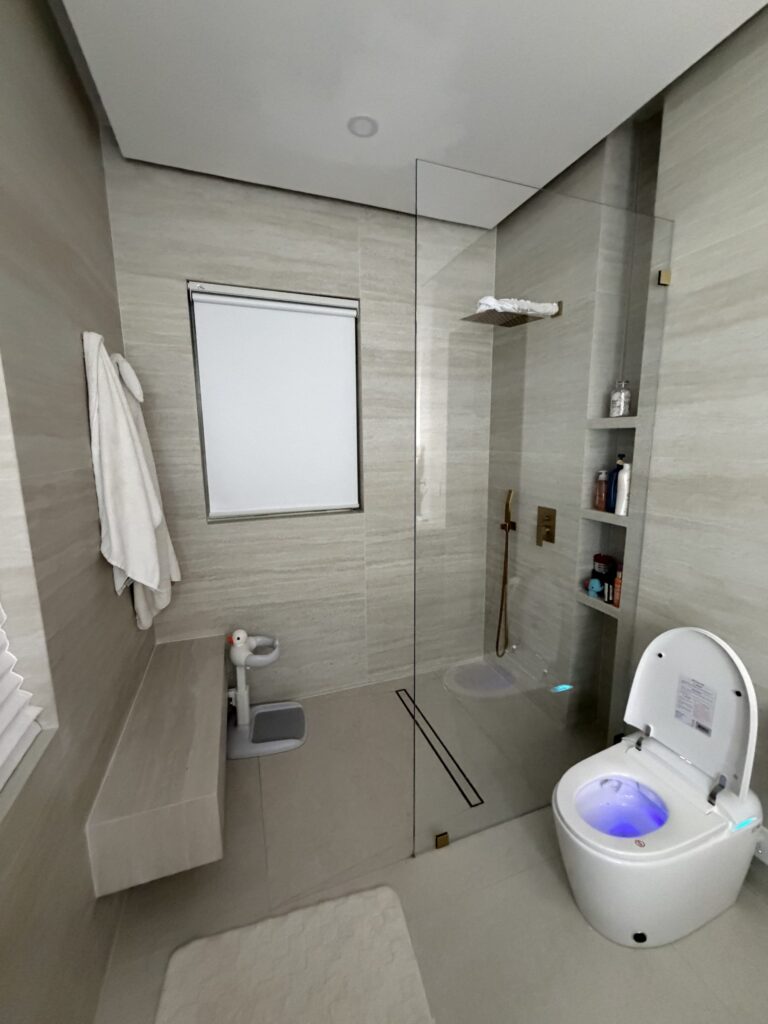 Walk-in shower with a frameless glass screen and brass fittings, opening directly off the bathroom floor with no step