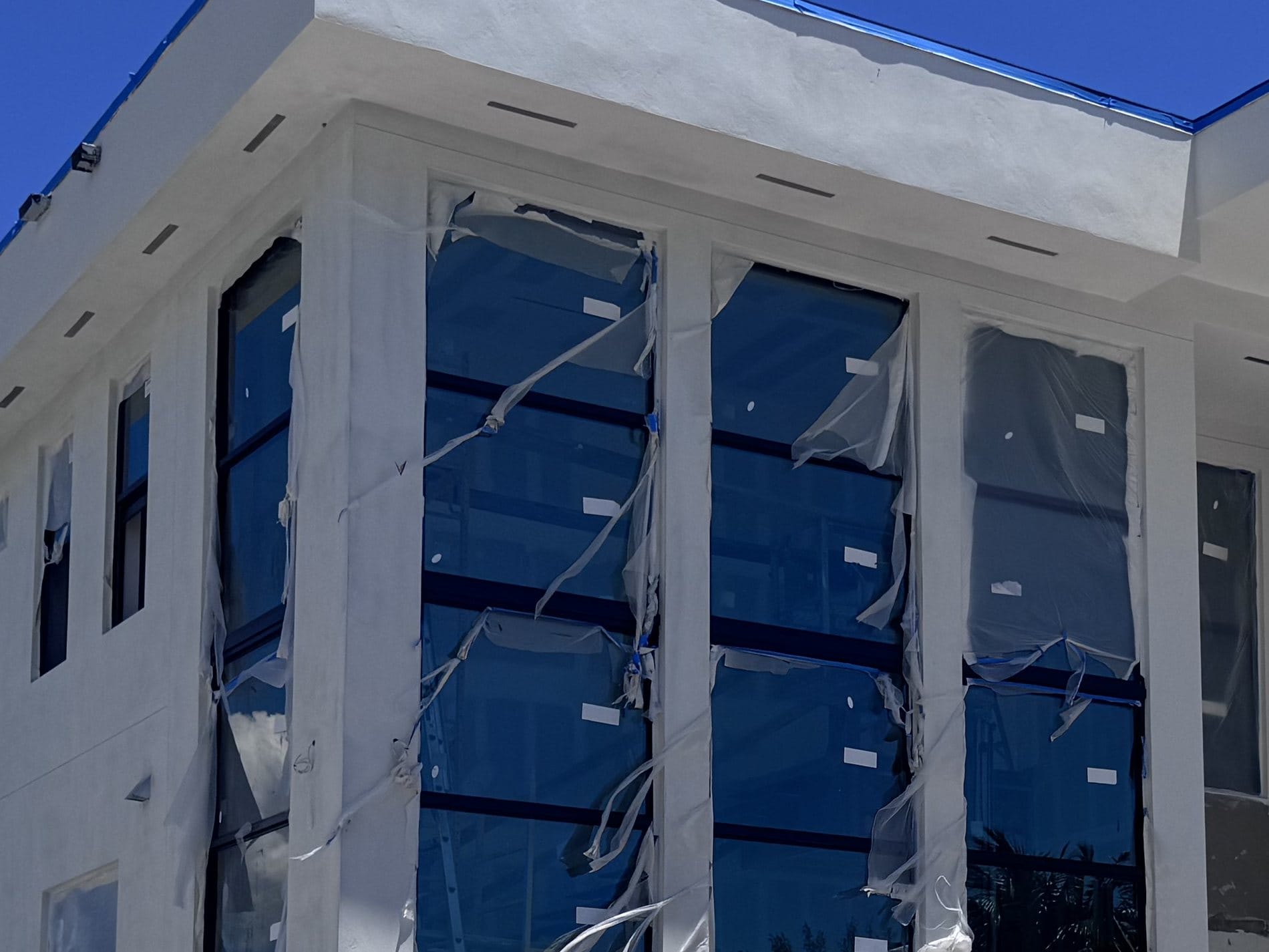 Close-up of the corner glazing head detail, protective film and setting-block markers still on the glass