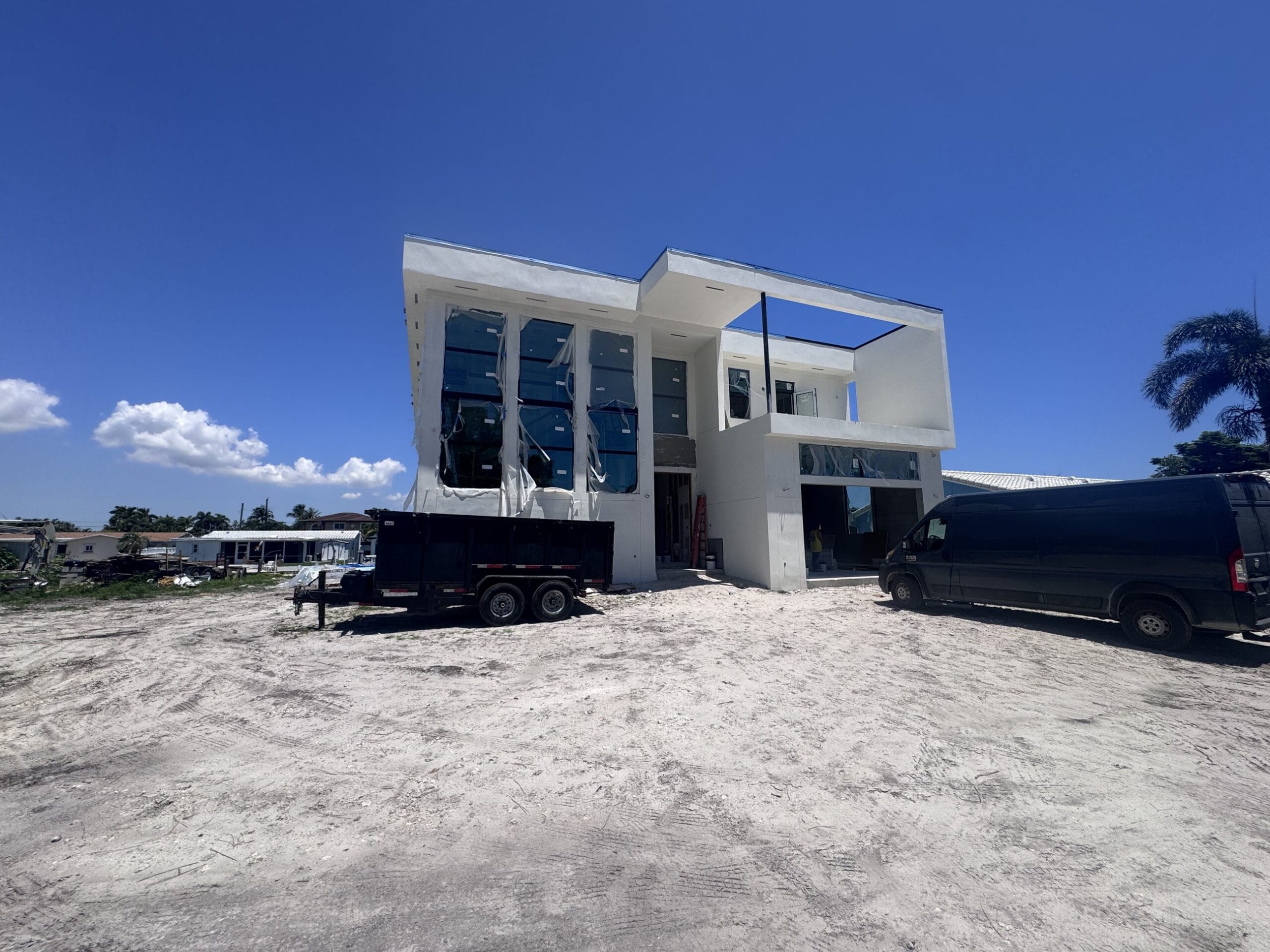 Wide view of the new-construction site with the house shell complete and the lot still un-graded