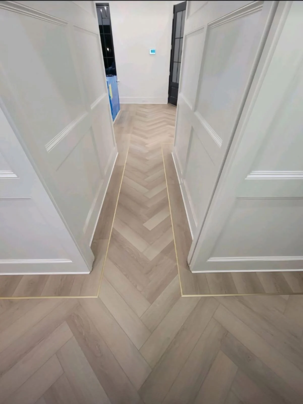 Herringbone flooring laid through a hallway and entrance