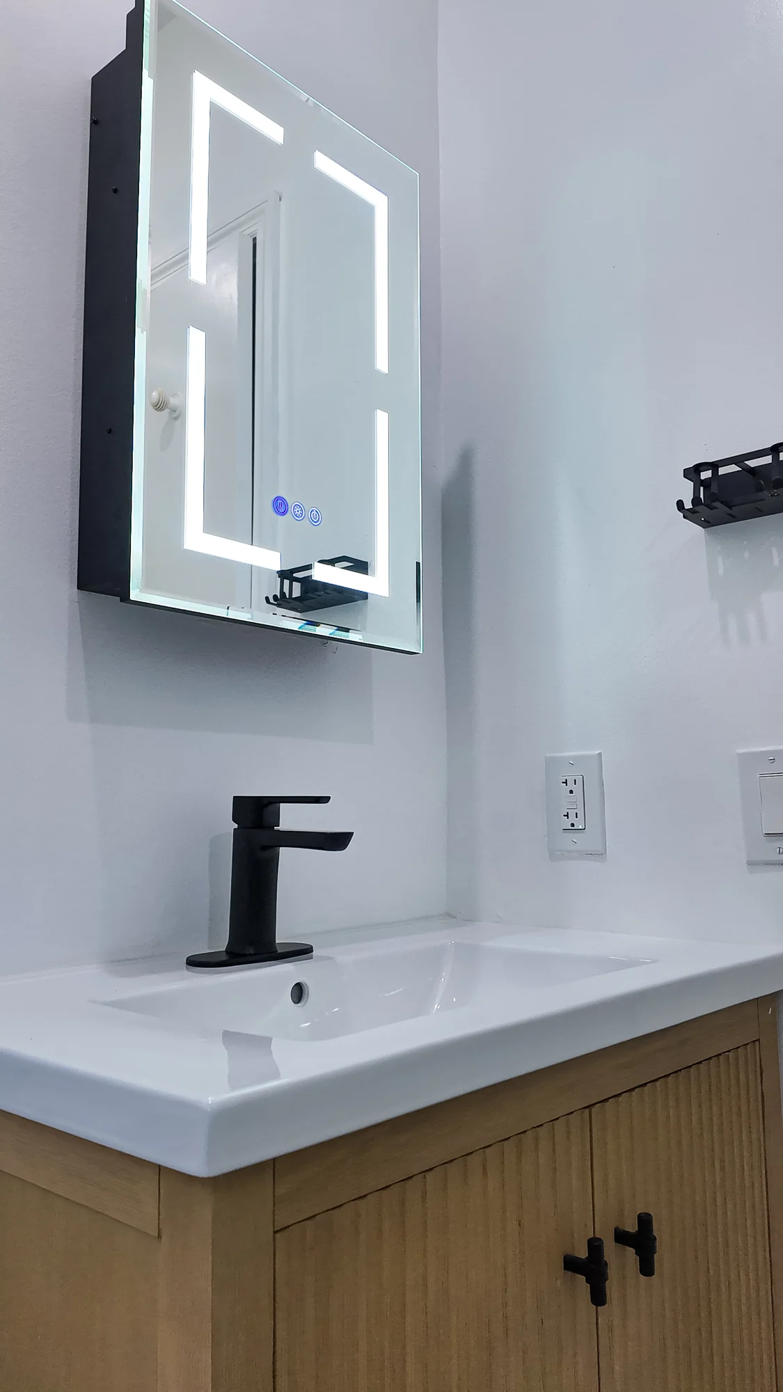 Compact bathroom vanity with a lit mirror and black tap