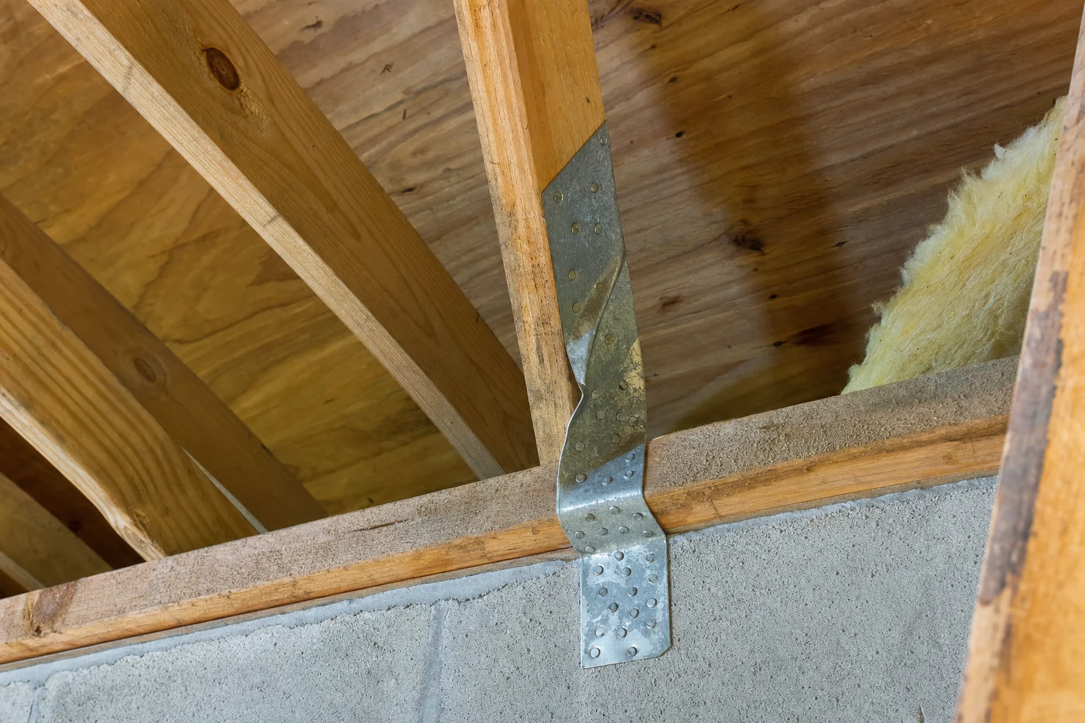 Metal hurricane tie connecting a roof truss to the wall top plate