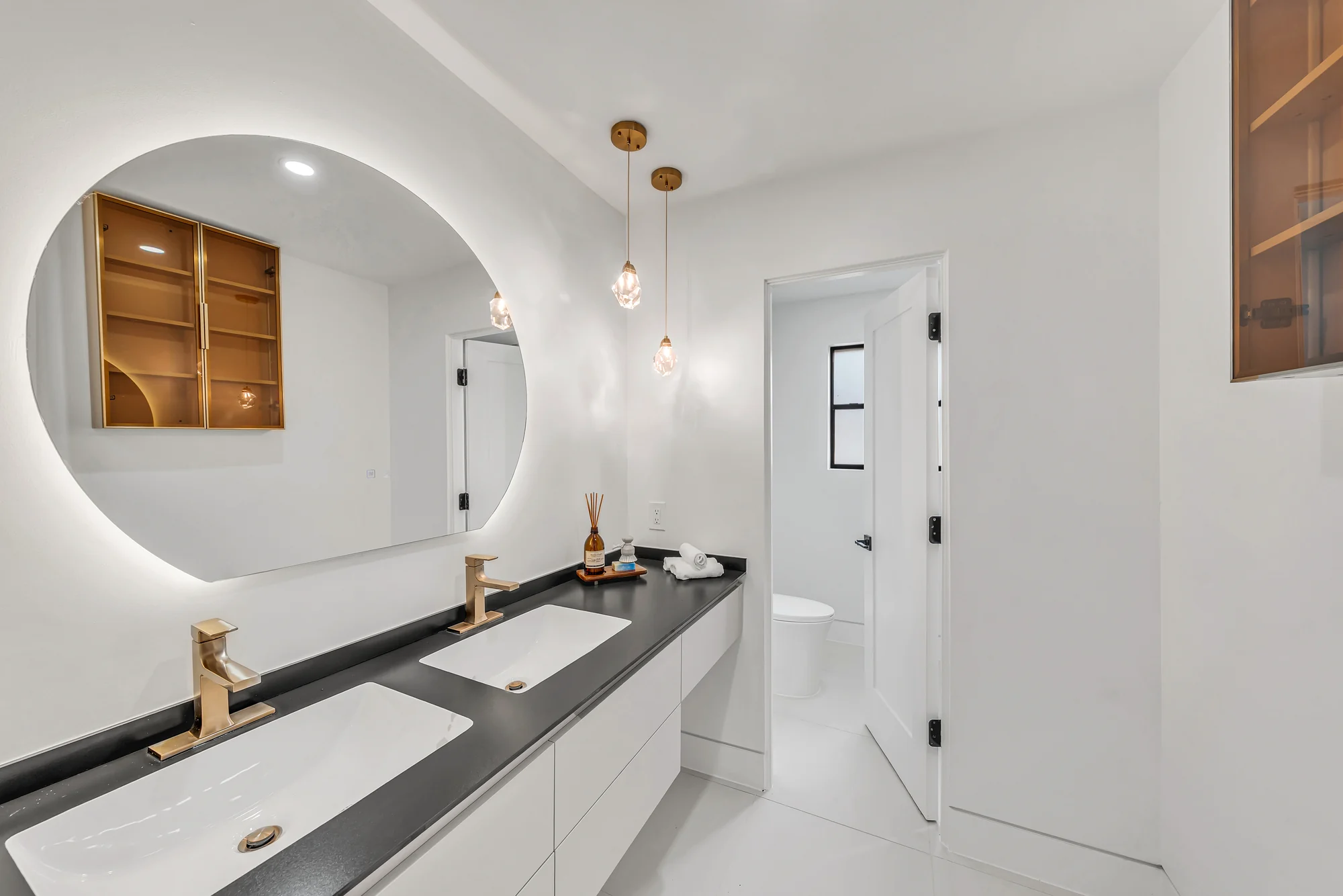 Renovated bathroom with round mirror and twin basins