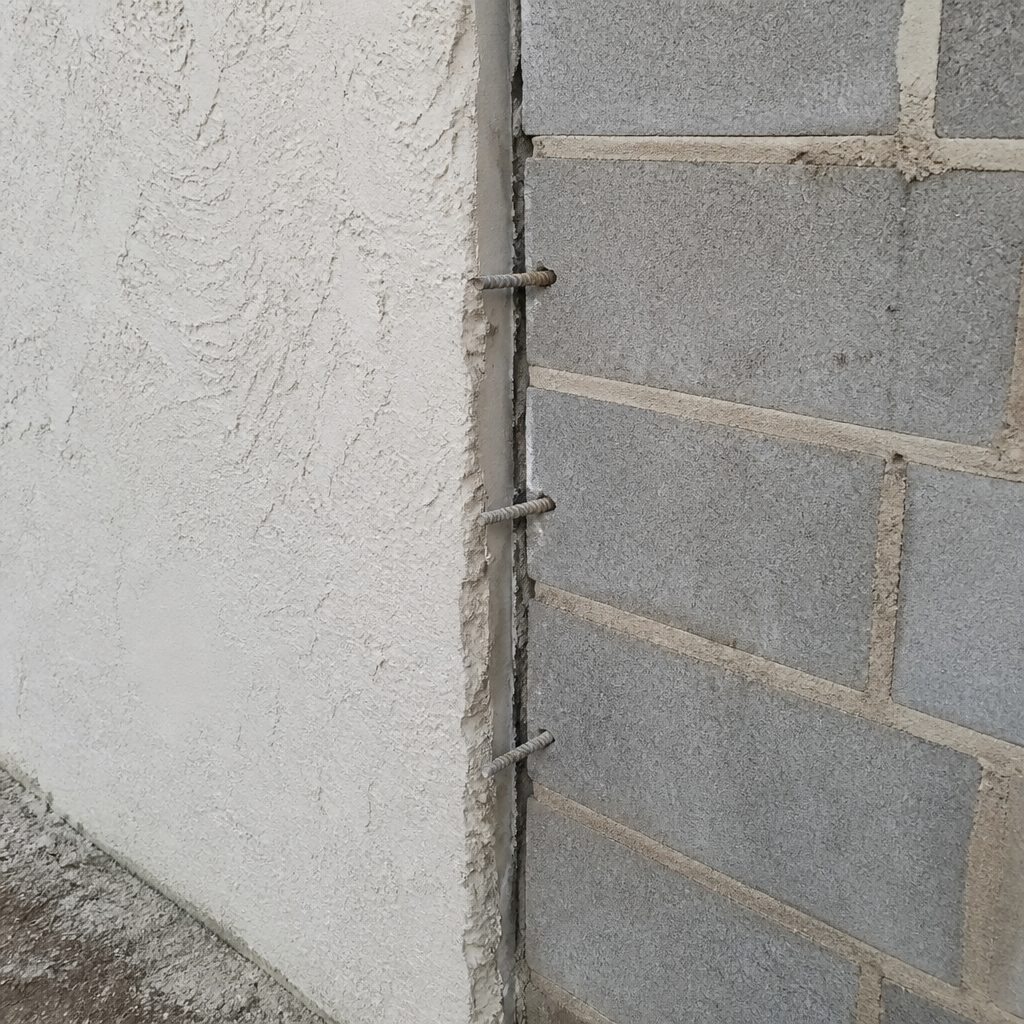 AI-generated illustration: reinforcing dowels tying a new masonry addition into an existing exterior wall