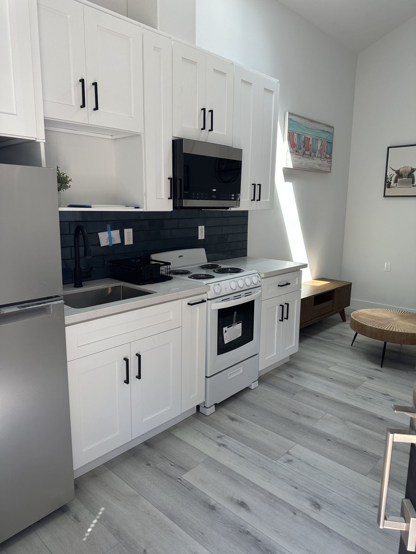 Compact ADU kitchen with white shaker cabinetry, dark subway tile and a full-height range