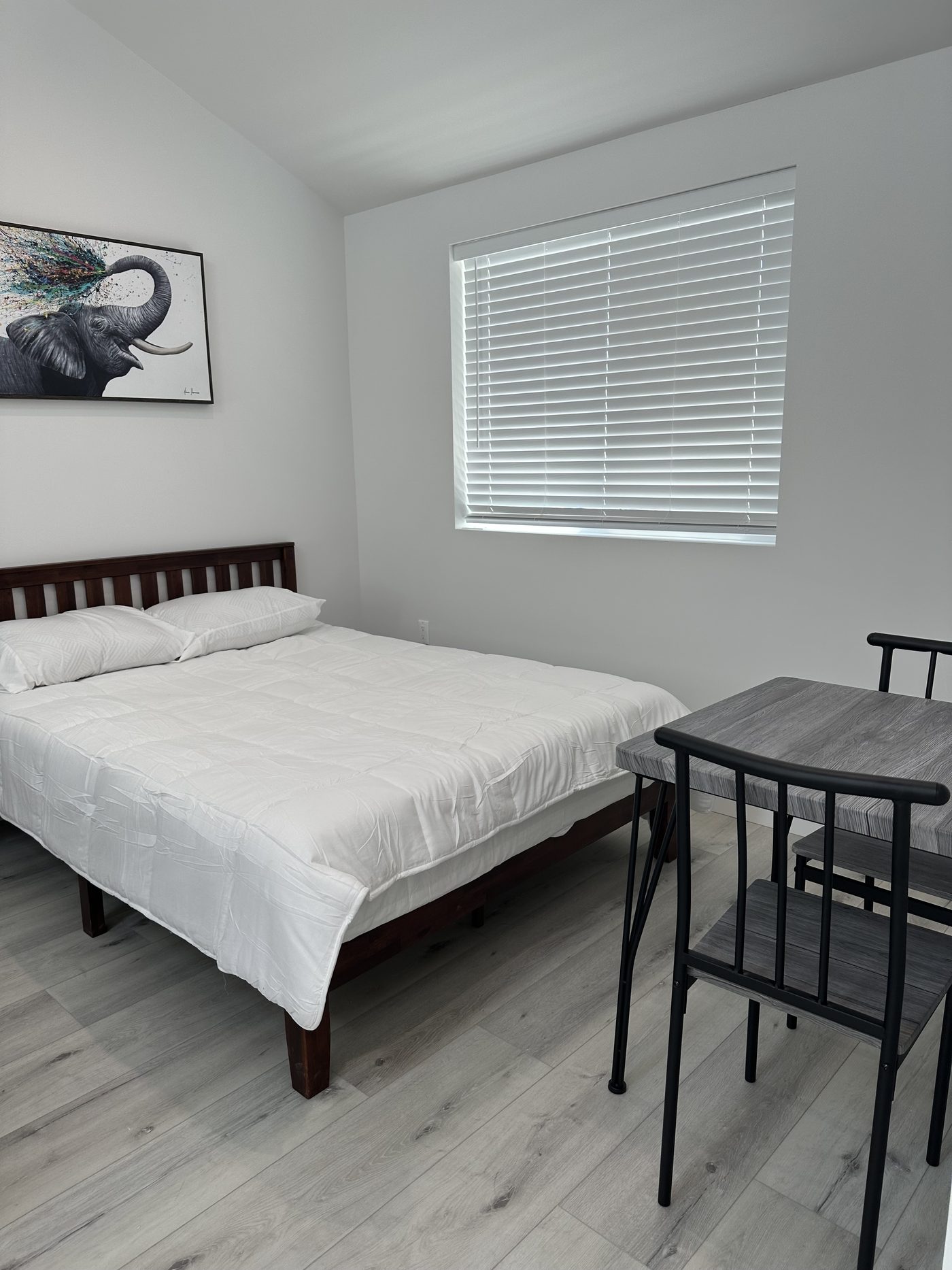 Sleeping area of a studio ADU with a shuttered window and a compact dining table