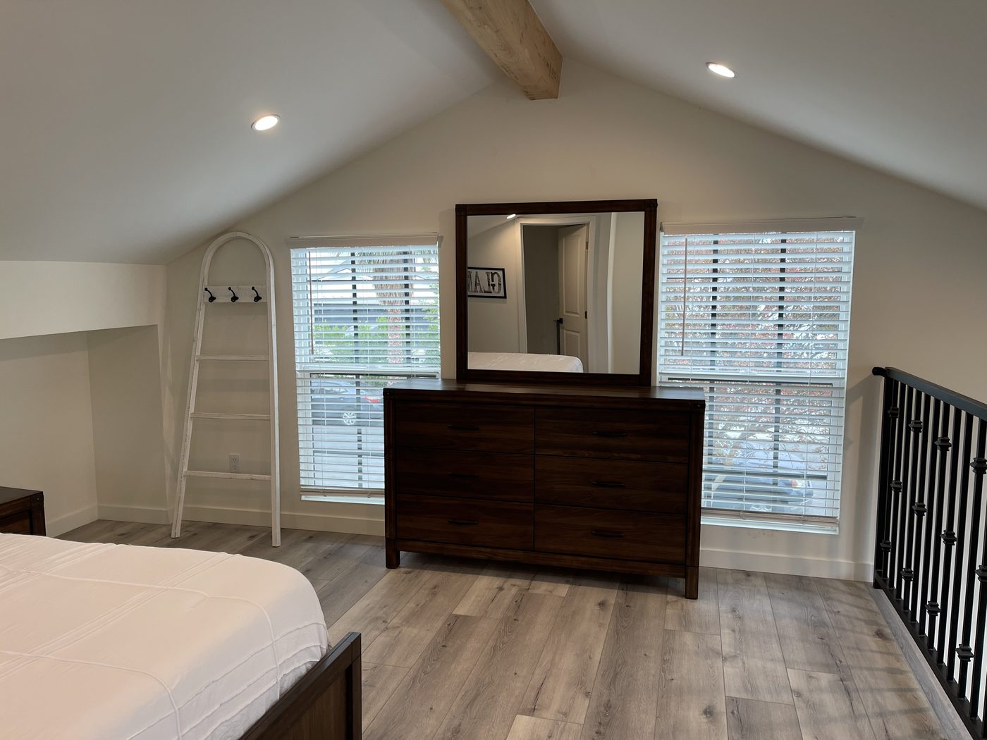 ADU bedroom with a dresser and mirror beside the loft gallery rail