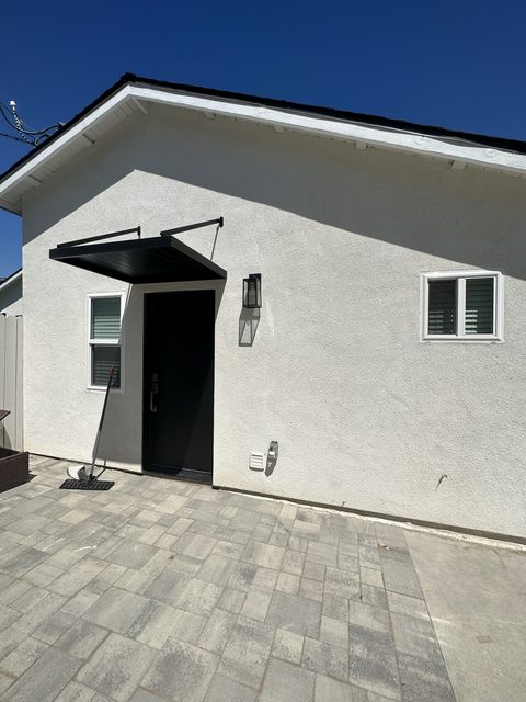 Exterior of a finished detached ADU with white stucco and black trim