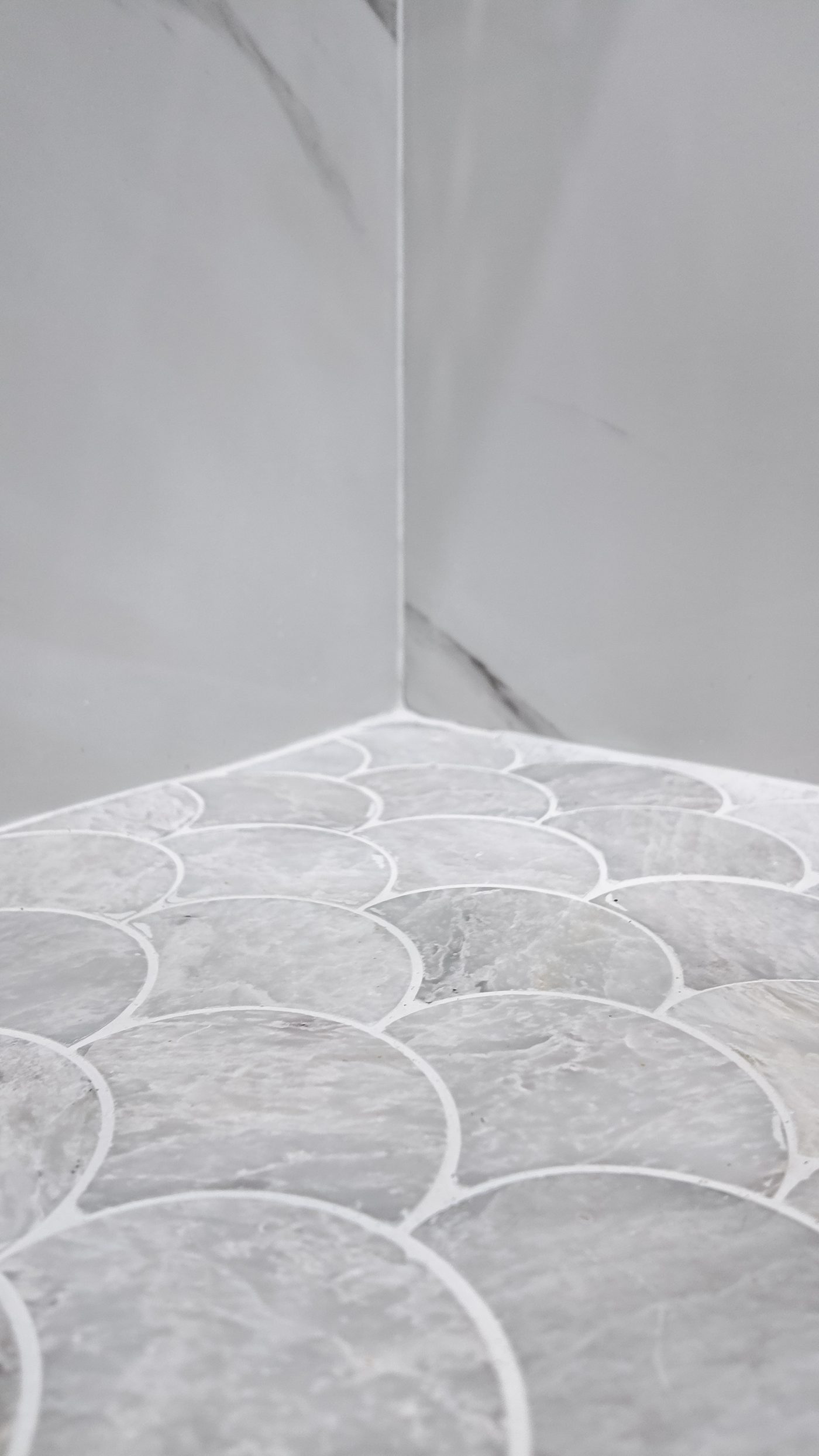 Shower floor mosaic meeting the large-format wall tile at the corner