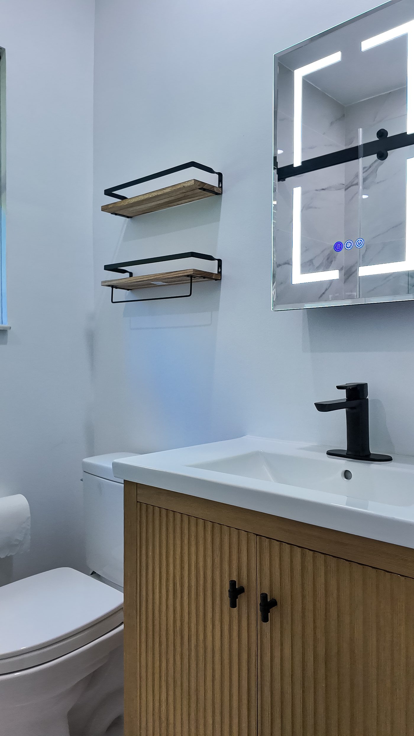 Vanity, mirror cabinet and open black shelving seen across the bathroom