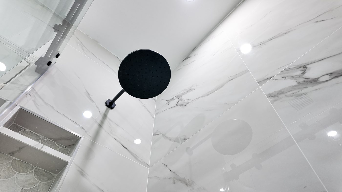 Rain head and recessed niche in a marble-look porcelain shower