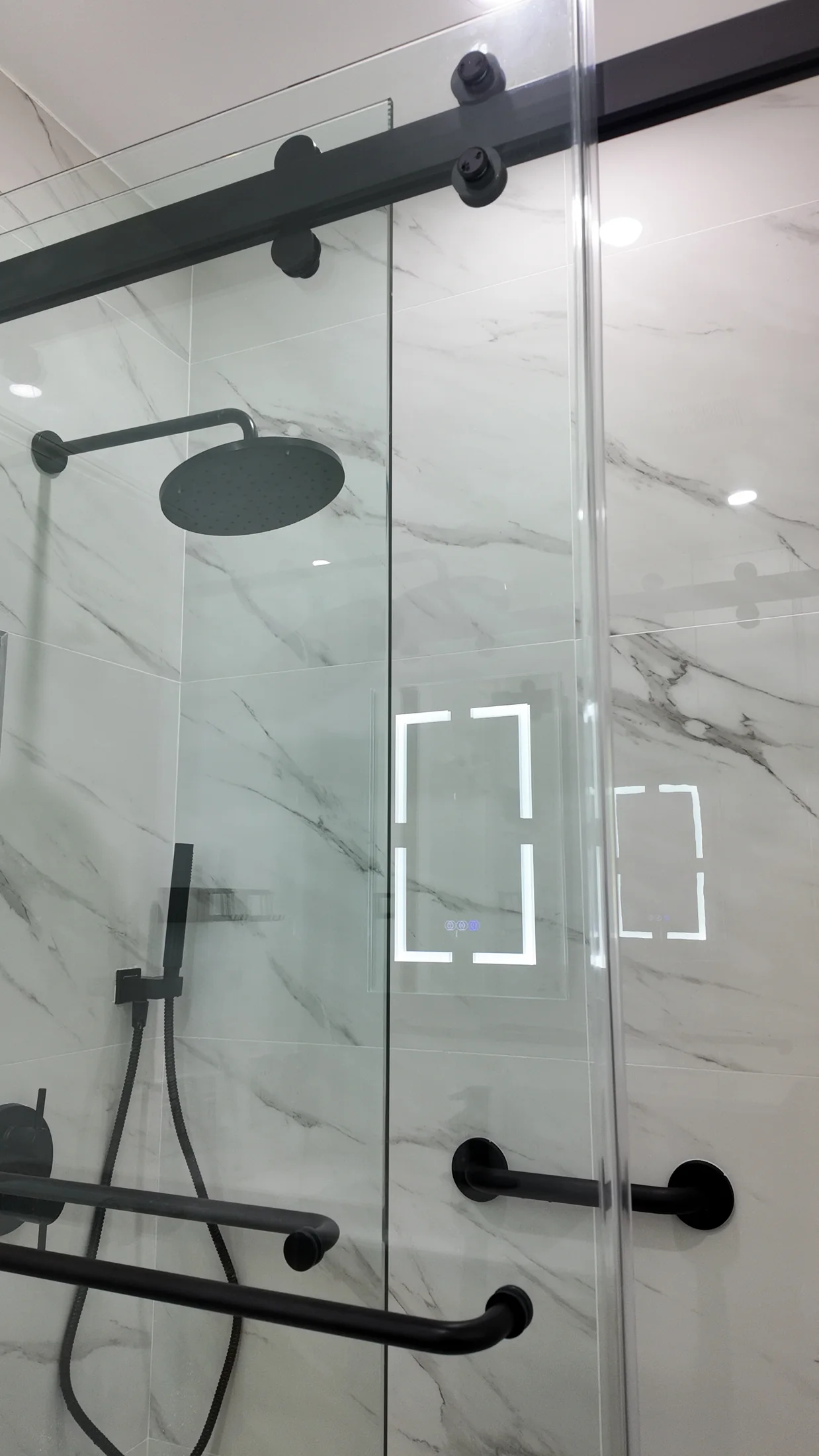 Rain shower head and matt black mixer set against large-format marble-look tile