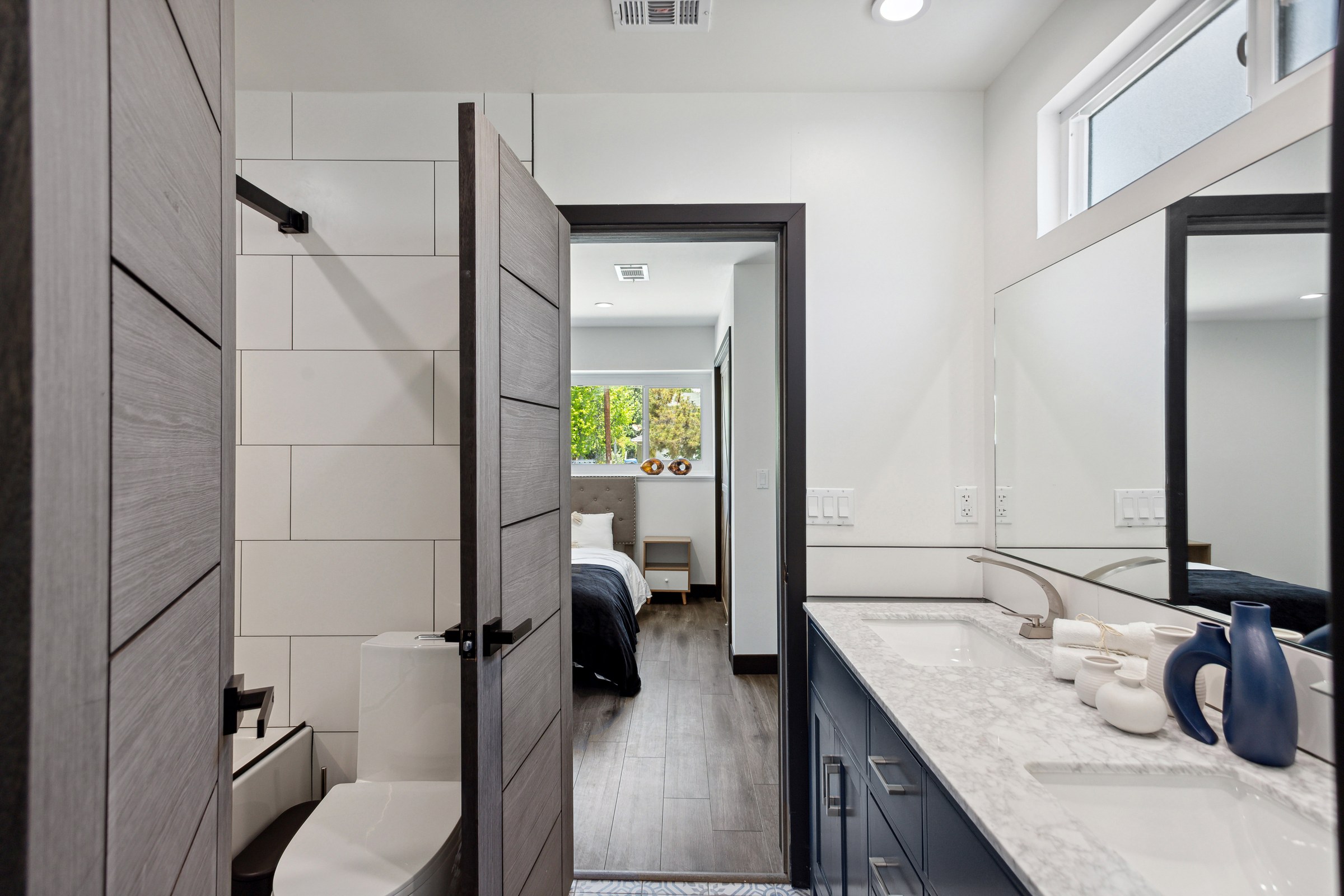 Bathroom remodel with a navy double vanity, marble countertop and a tiled walk-in shower