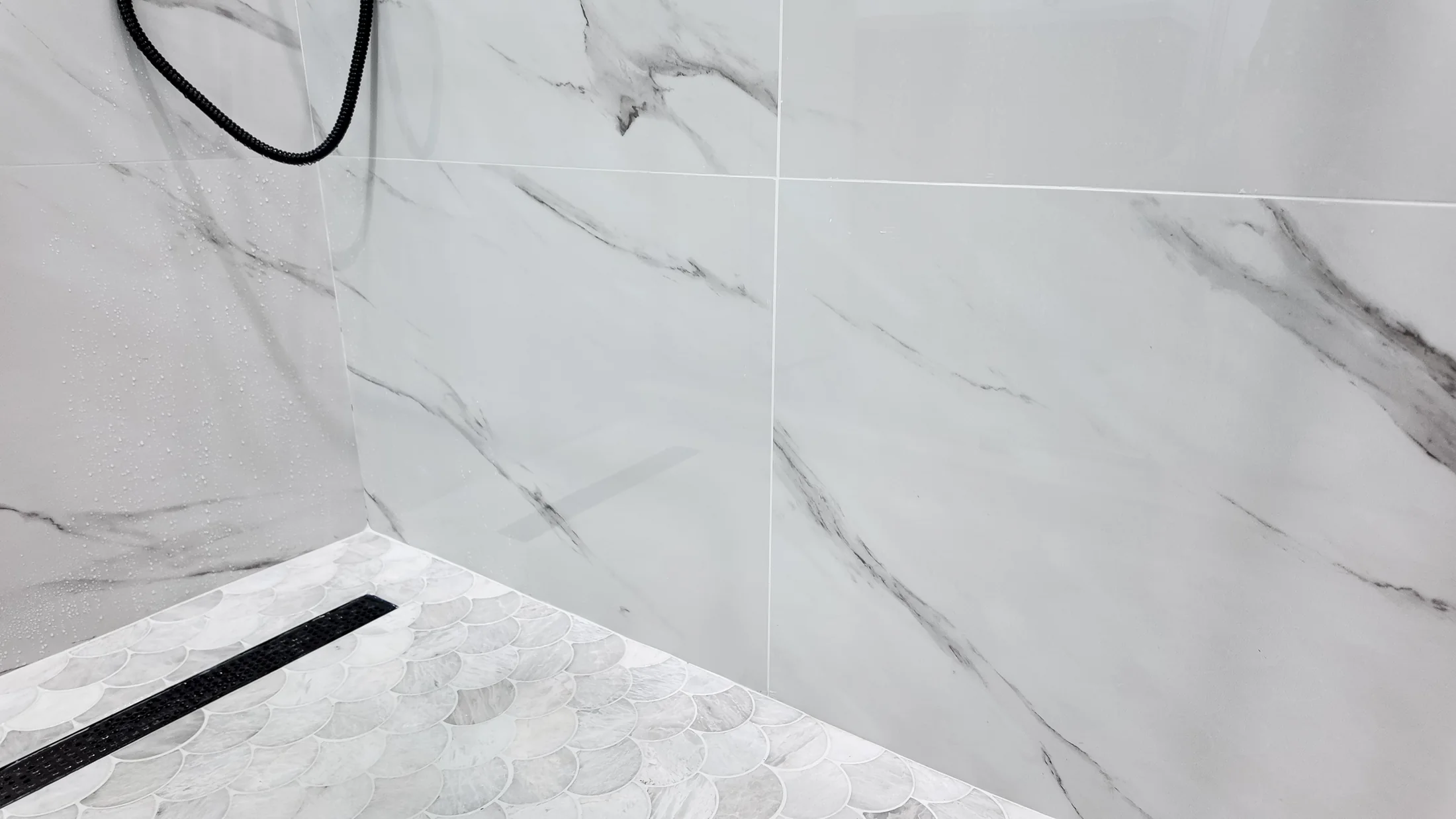 Shower enclosure showing the tiled wall run and a linear drain at the threshold