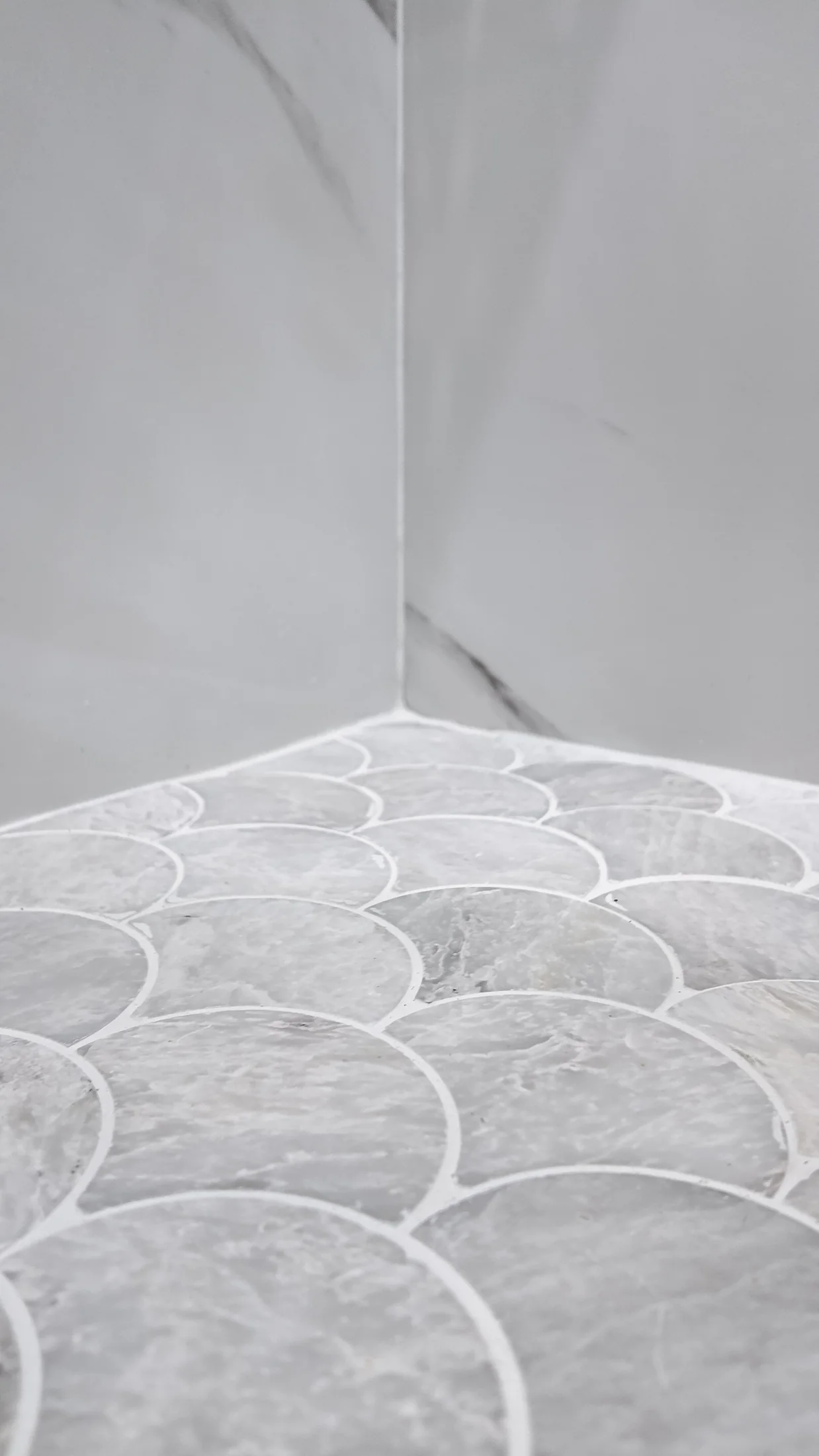 Shower threshold where the mosaic floor meets the large-format wall tile