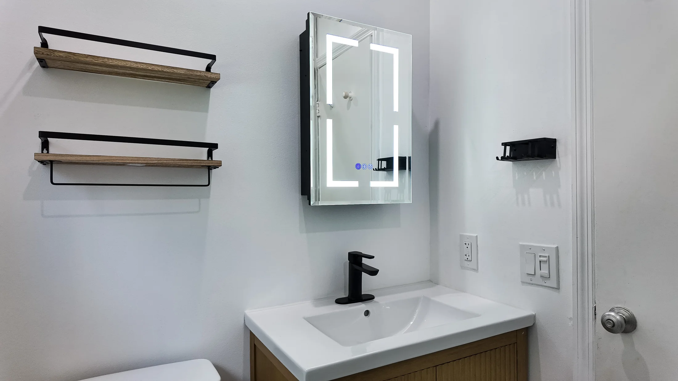 Vanity run with a backlit mirror cabinet and open shelving alongside