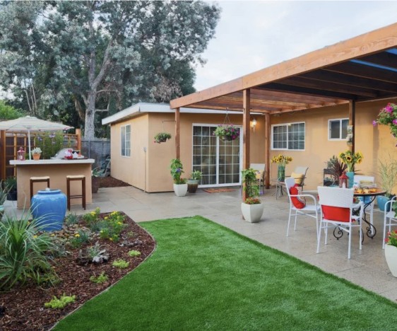 Covered outdoor pergola with dining and bar seating, and a turfed backyard