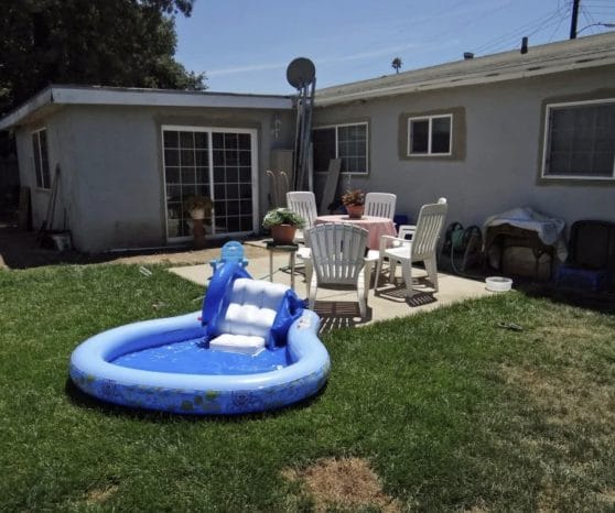 Backyard with worn lawn and open patio, before renovation