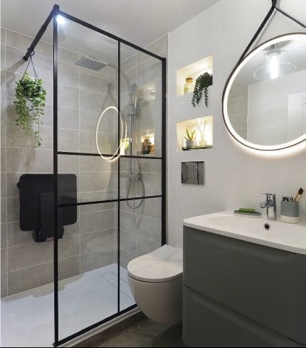 Renovated bathroom with frameless glass shower and round backlit mirror