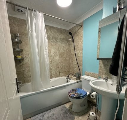 Dated bathroom with alcove tub and shower curtain, before renovation
