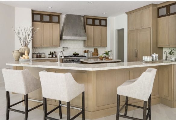 Renovated kitchen with light cabinetry, range hood and island seating