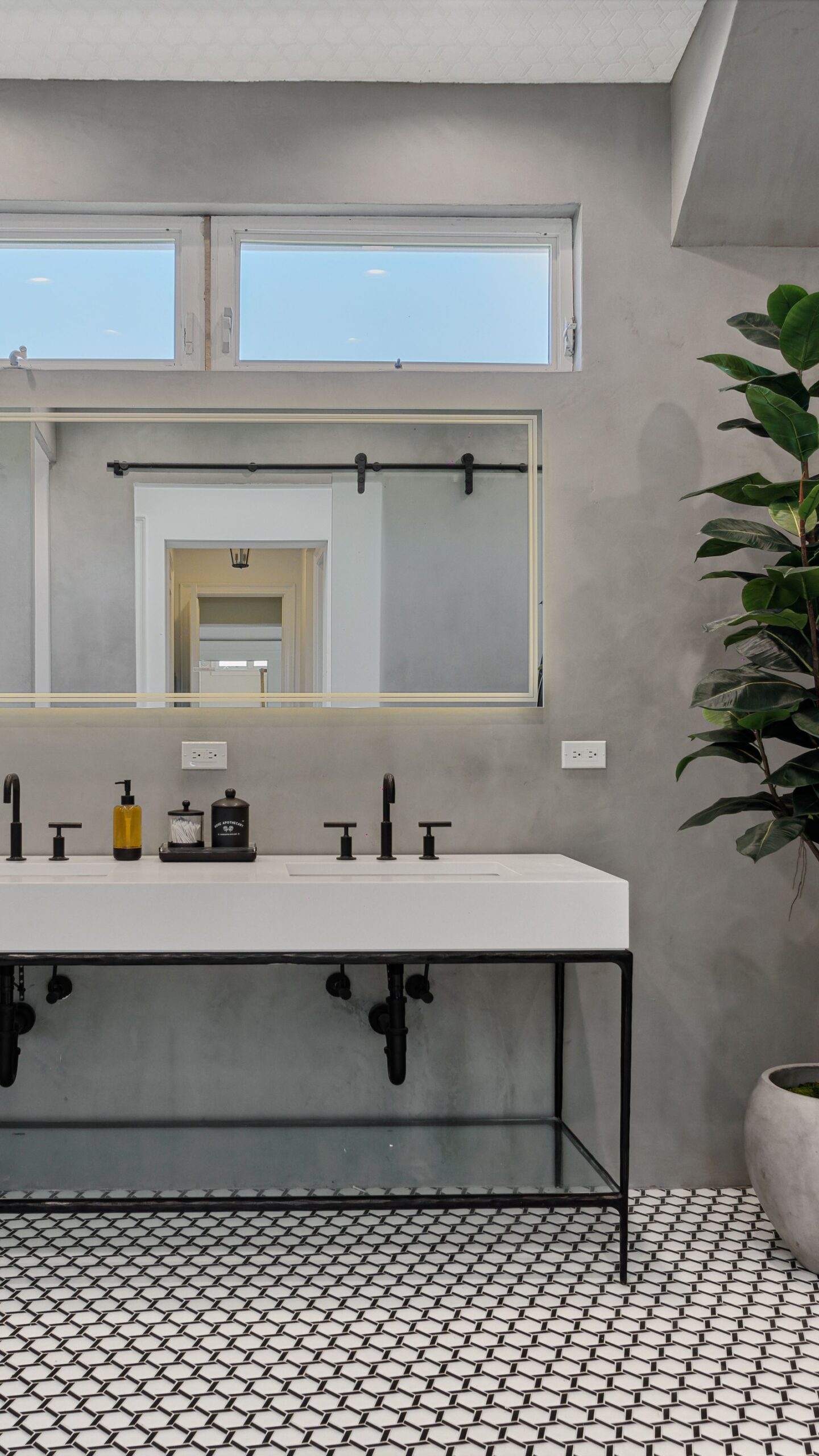 Modern concrete bathroom with matte black fixtures, geometric mosaic floor and glass walk-in shower