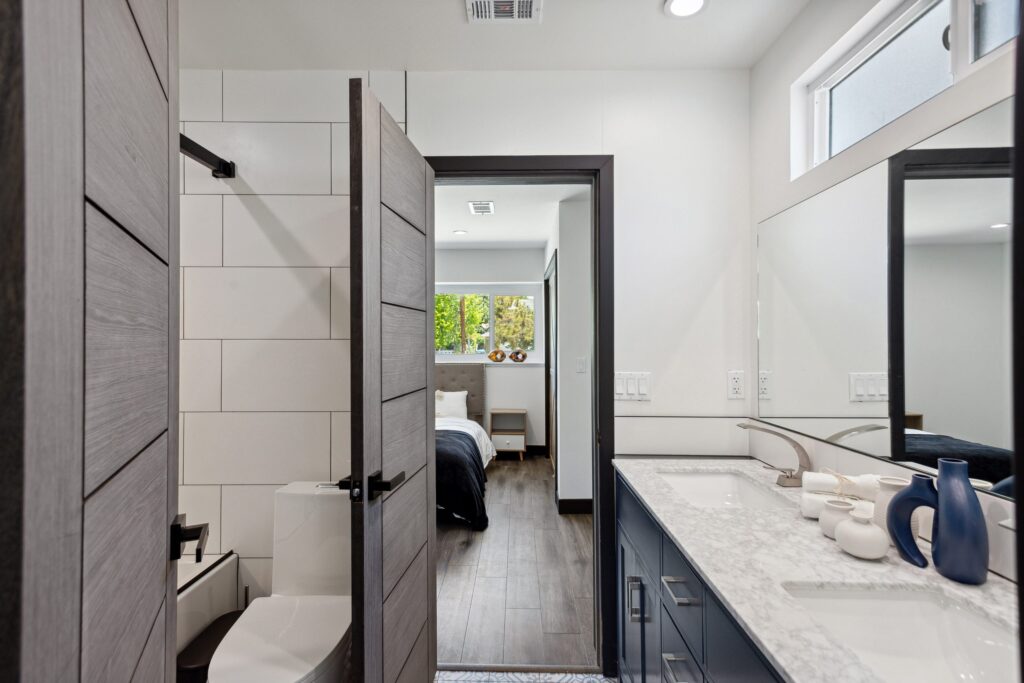 Bathroom remodel by Elbaz Construction in South Florida: large-format white wall tile, matt black brassware, a blue shaker vanity with a marble top and a patterned floor