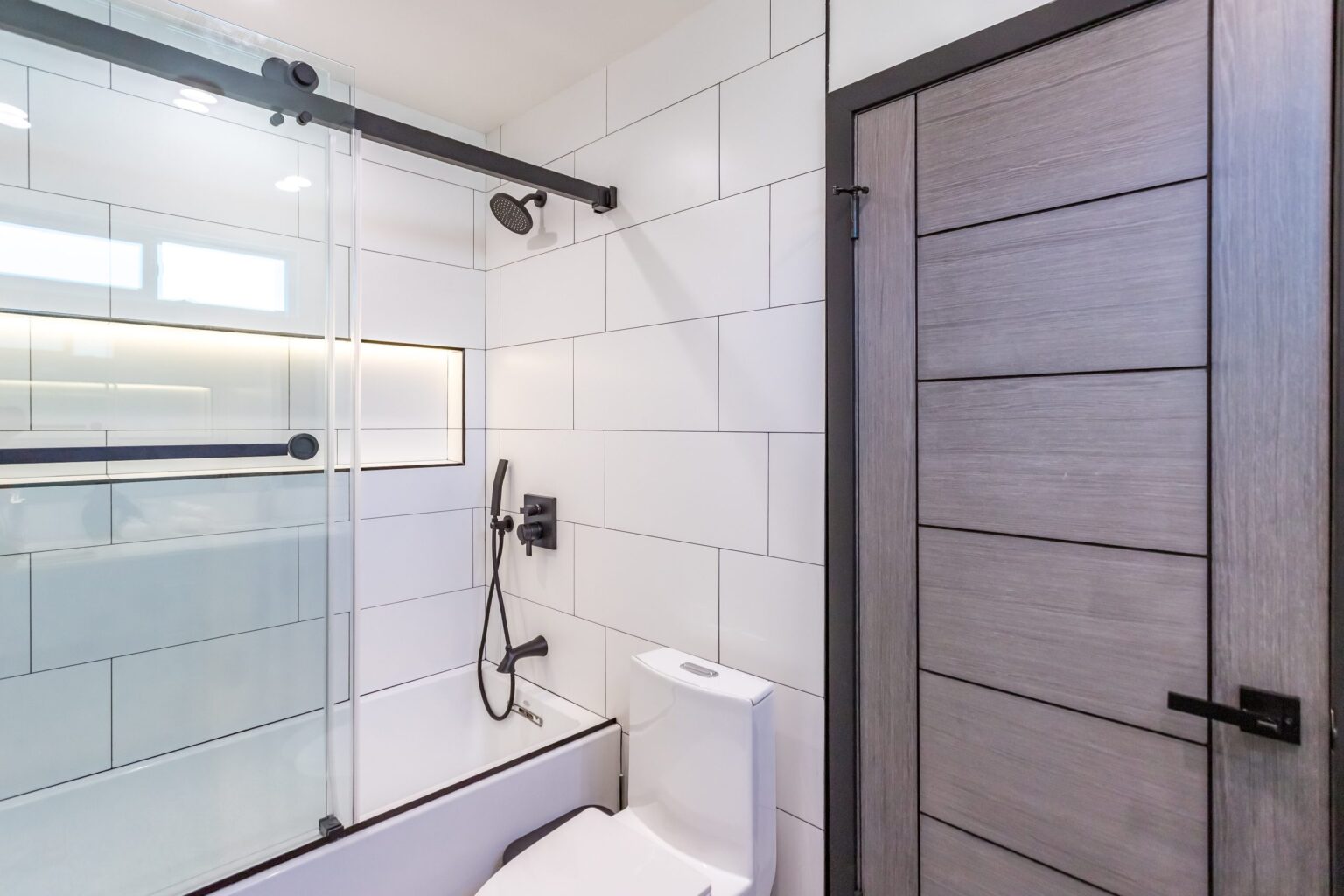 Bathroom remodel by Elbaz Construction in South Florida: large-format white wall tile, matt black brassware, a blue shaker vanity with a marble top and a patterned floor