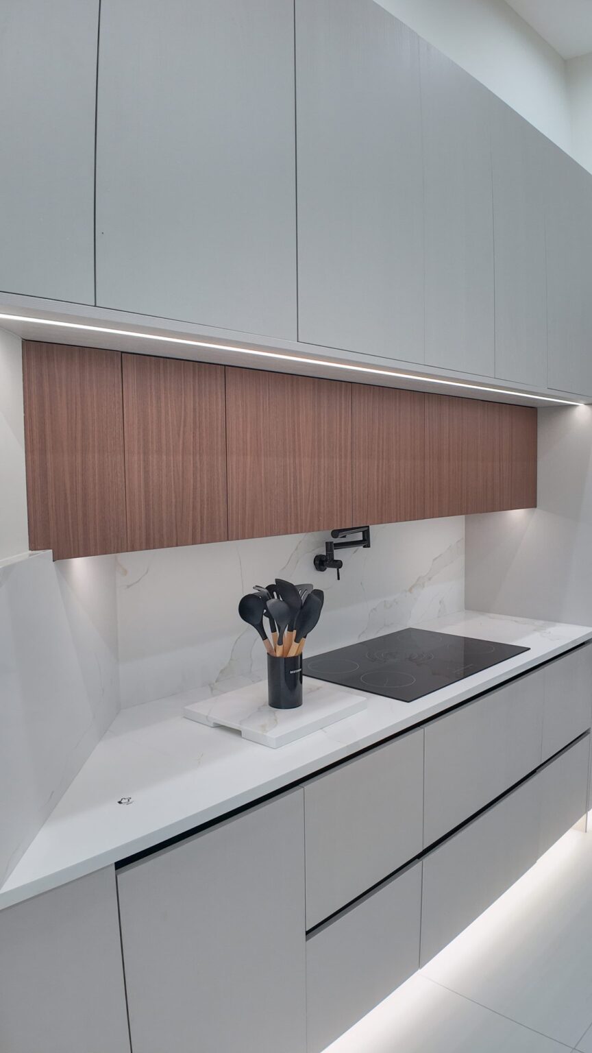 Open-plan kitchen and living remodel by Elbaz Construction in South Florida: handleless cabinetry, walnut wall units, large-format porcelain worktops and a screened terrace beyond the glazing