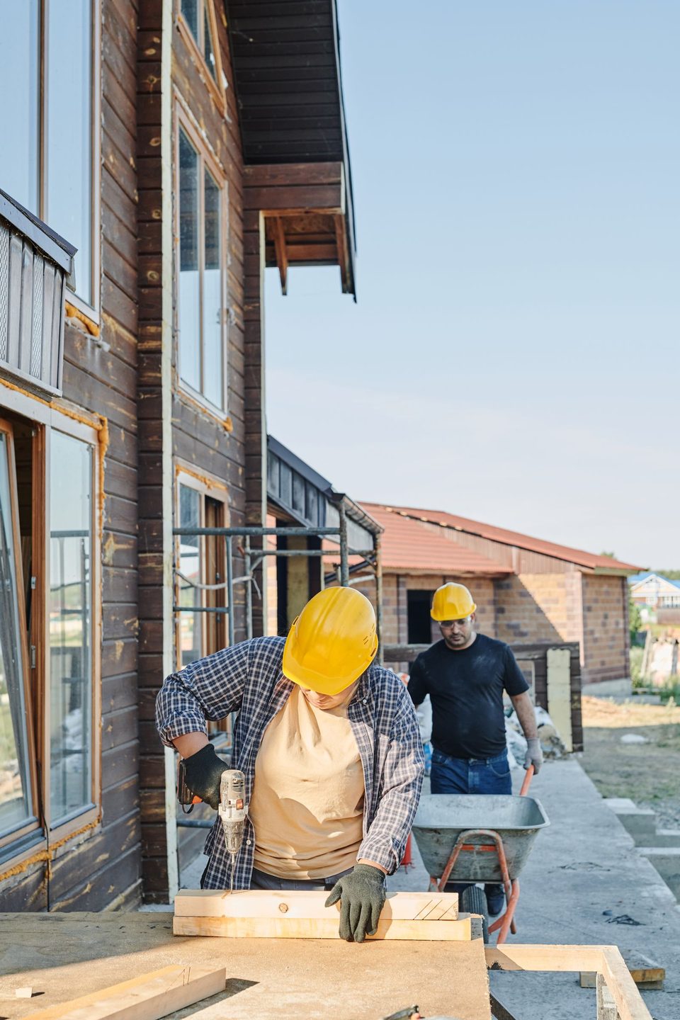 Two workers in hard hats fastening framing lumber on site