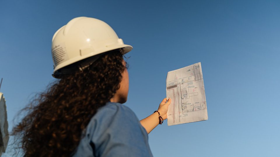 Site visit with plans held up against the building