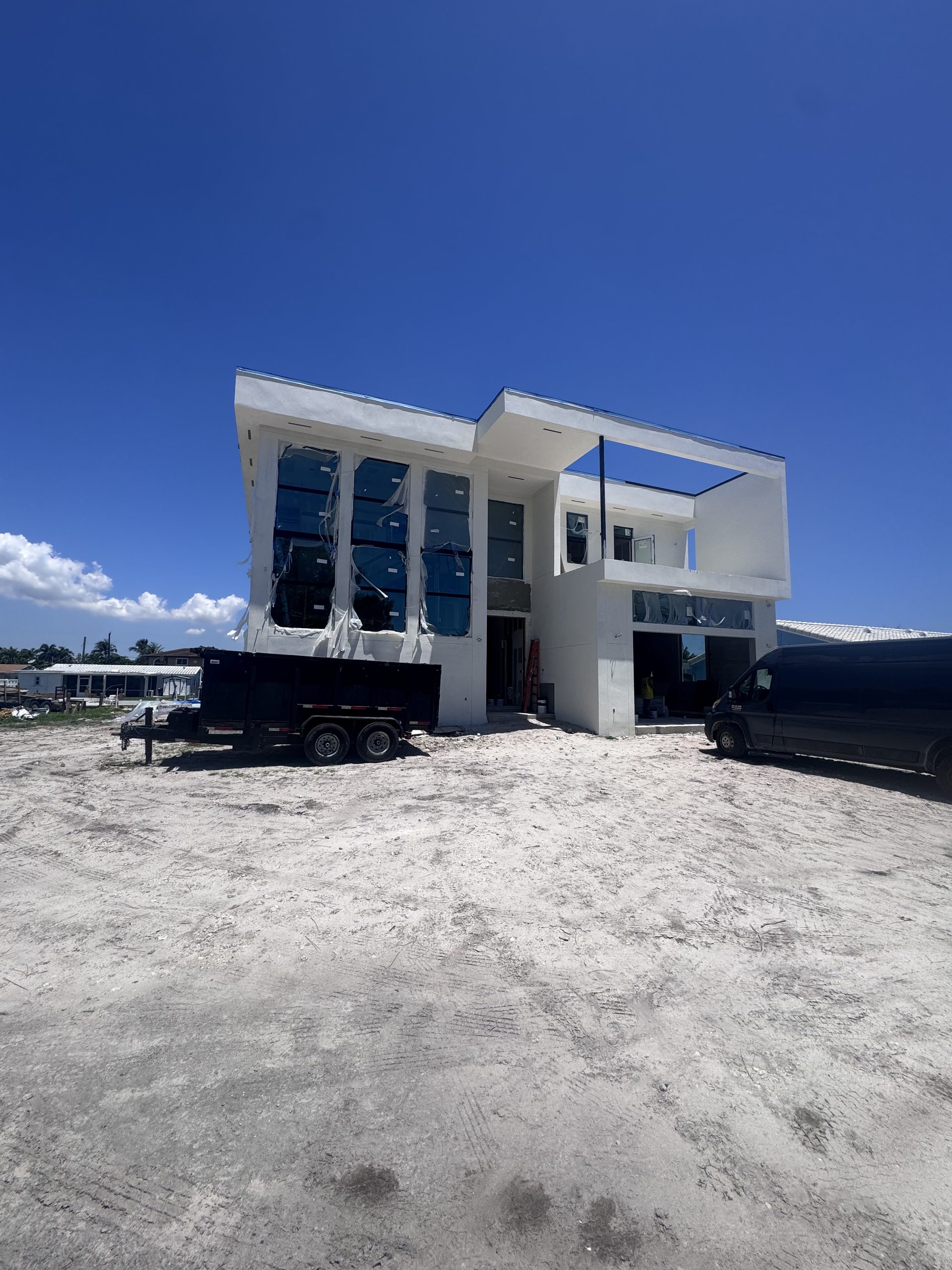 Completed two-storey Elbaz Construction custom home with a dark-framed glazed upper storey, photographed from the street