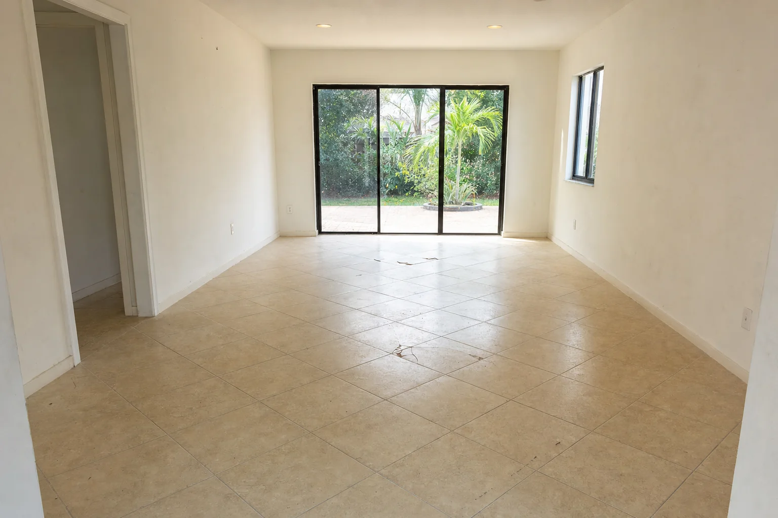 Illustration of a dated beige tile floor with cracked tiles in an empty South Florida room before removal begins
