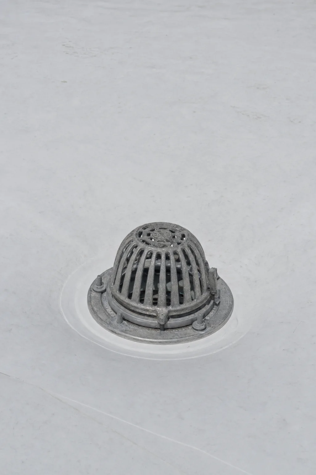 Illustration of a roof drain set into a tapered sump with the membrane clamped and a domed strainer fitted