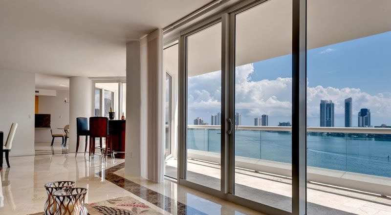 Impact window and sliding glass door installation by Elbaz Construction across South Florida: aluminium-framed impact glazing in stucco openings, on waterfront and single-storey homes