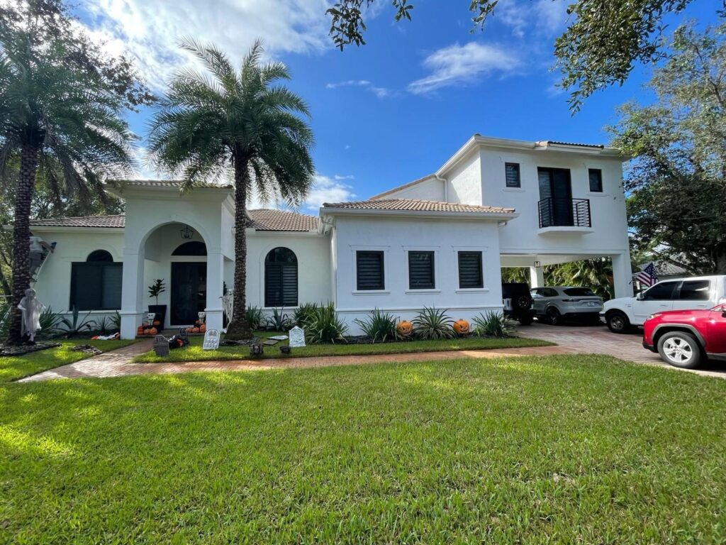 Impact window and sliding glass door installation by Elbaz Construction across South Florida: aluminium-framed impact glazing in stucco openings, on waterfront and single-storey homes