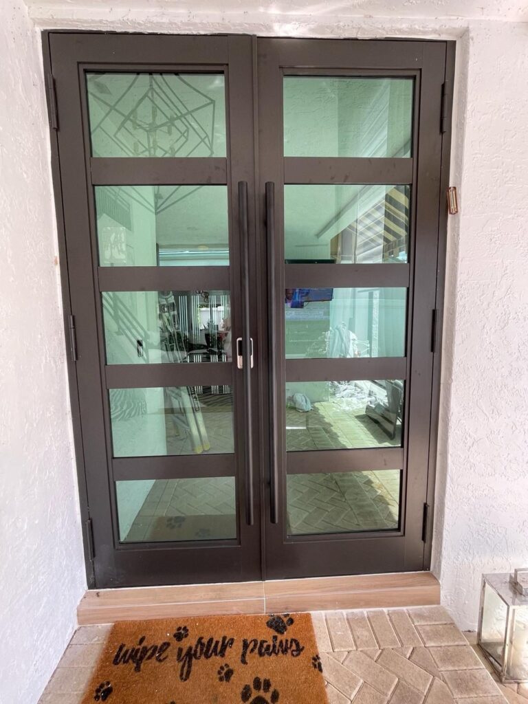 Impact window and sliding glass door installation by Elbaz Construction across South Florida: aluminium-framed impact glazing in stucco openings, on waterfront and single-storey homes